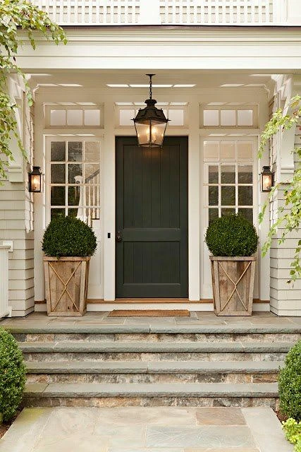Front entry with a deep green door and boxwood topiaries