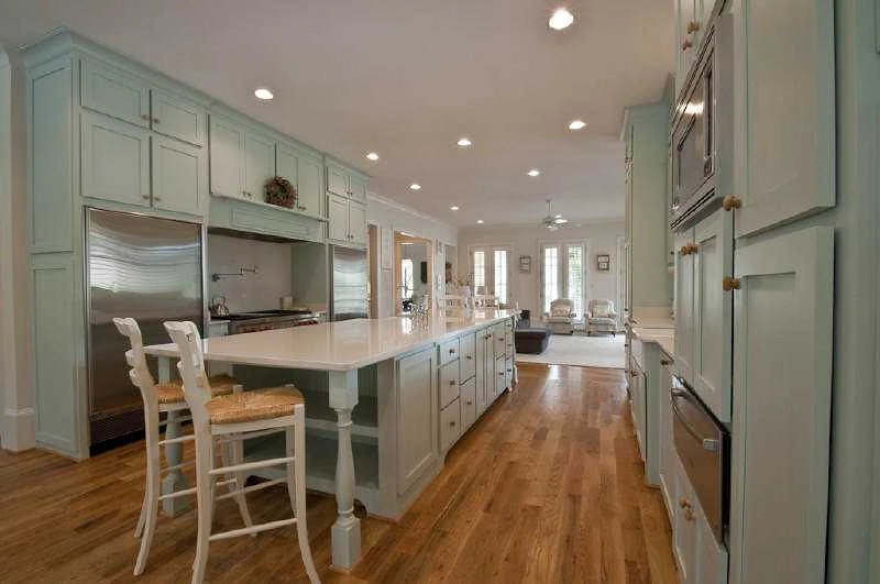 Kitchen with sage green cabinetry, a long island and hardwood floors