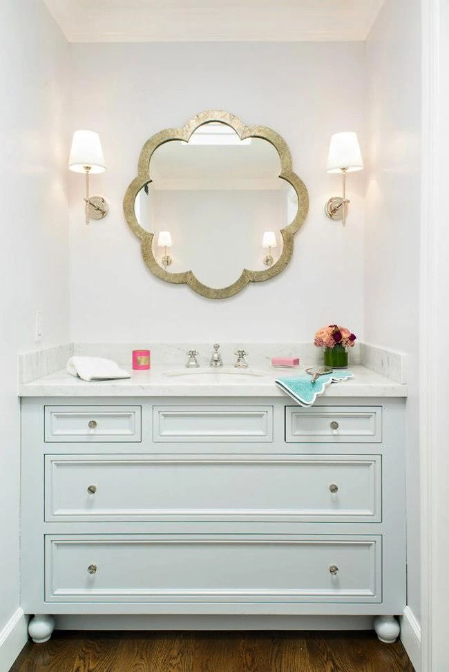 Powder room with a scalloped gilt mirror and a white marble-topped vanity